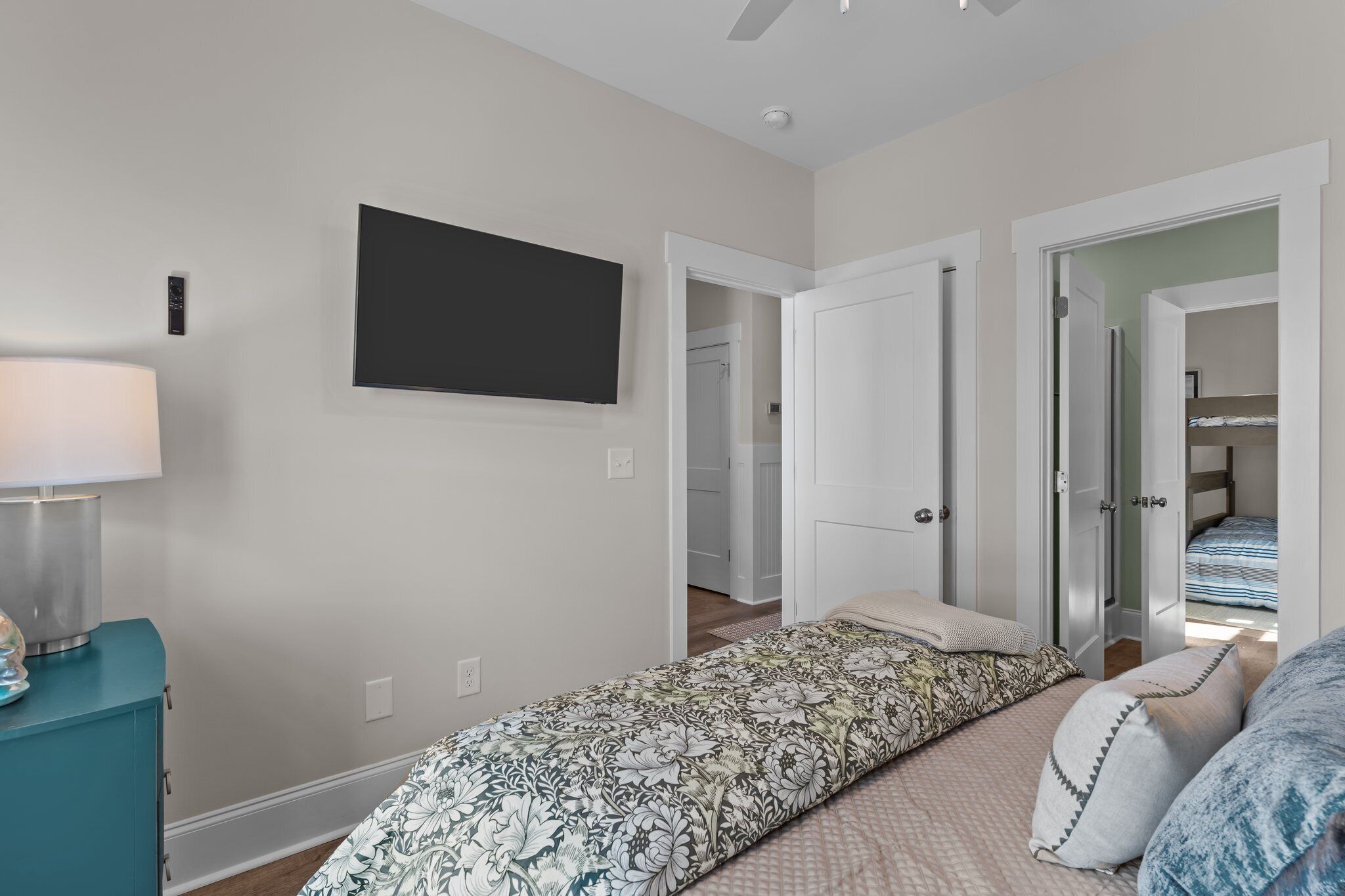 Un dormitorio con cama, televisor montado en la pared y puerta que da a un baño.