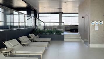 Una piscina cubierta, una piscina al aire libre, sombrillas, tumbonas