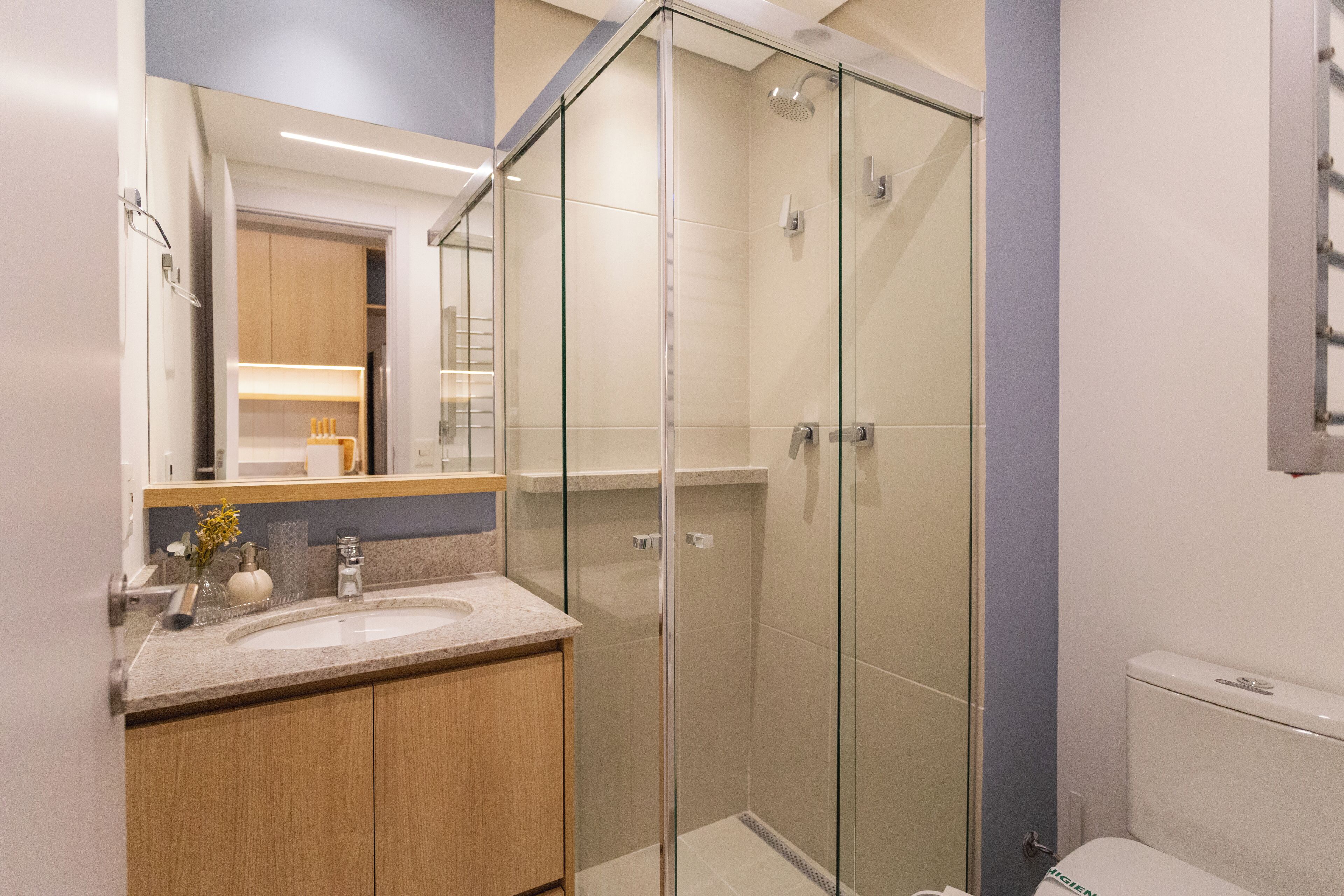 A modern bathroom with a glass shower enclosure, a sink with a marble countertop, and a toilet.