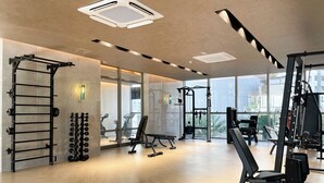 Un gimnasio amplio con diversos equipos de ejercicio, ventanas grandes y un diseño moderno.