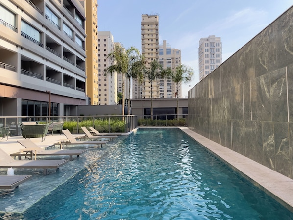 Una piscina techada, una piscina al aire libre, sombrillas
