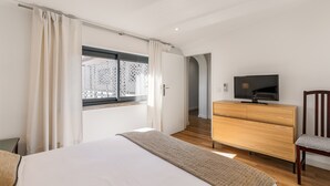 Une chambre à coucher avec un lit, une commode en bois, un téléviseur et une chaise.