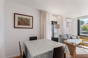 Quarto moderno com mesa de jantar, cadeiras, sofá e uma janela grande.