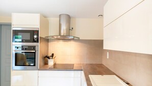 A modern kitchen with built-in appliances, a glass-top island, and a stainless steel range hood. - Gîte 'Gite Iago' with Private Terrace, Shared Garden and Wi-Fi (Larée)