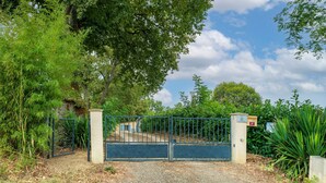 A gated entrance with a gravel path leading to a building. - Gîte 'Gite Iago' with Private Terrace, Shared Garden and Wi-Fi (Larée)