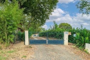 A gated entrance with a gravel path leading to a building. - Gîte 'Gite Iago' with Private Terrace, Shared Garden and Wi-Fi (Larée)