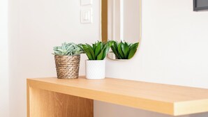 A bathroom with a wooden vanity, a white sink, two potted plants, a round white stool, and a mirror. - Casa Almika Sparano (Bari)