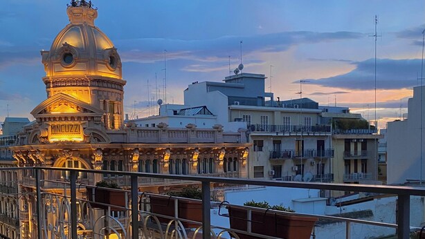 A balcony with a table and chairs, overlooking a cityscape with historic buildings and a river. - Casa Almika Sparano (Bari)