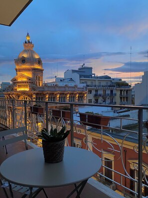A balcony with a table and chairs, overlooking a cityscape with historic buildings and a river. - Casa Almika Sparano (Bari)