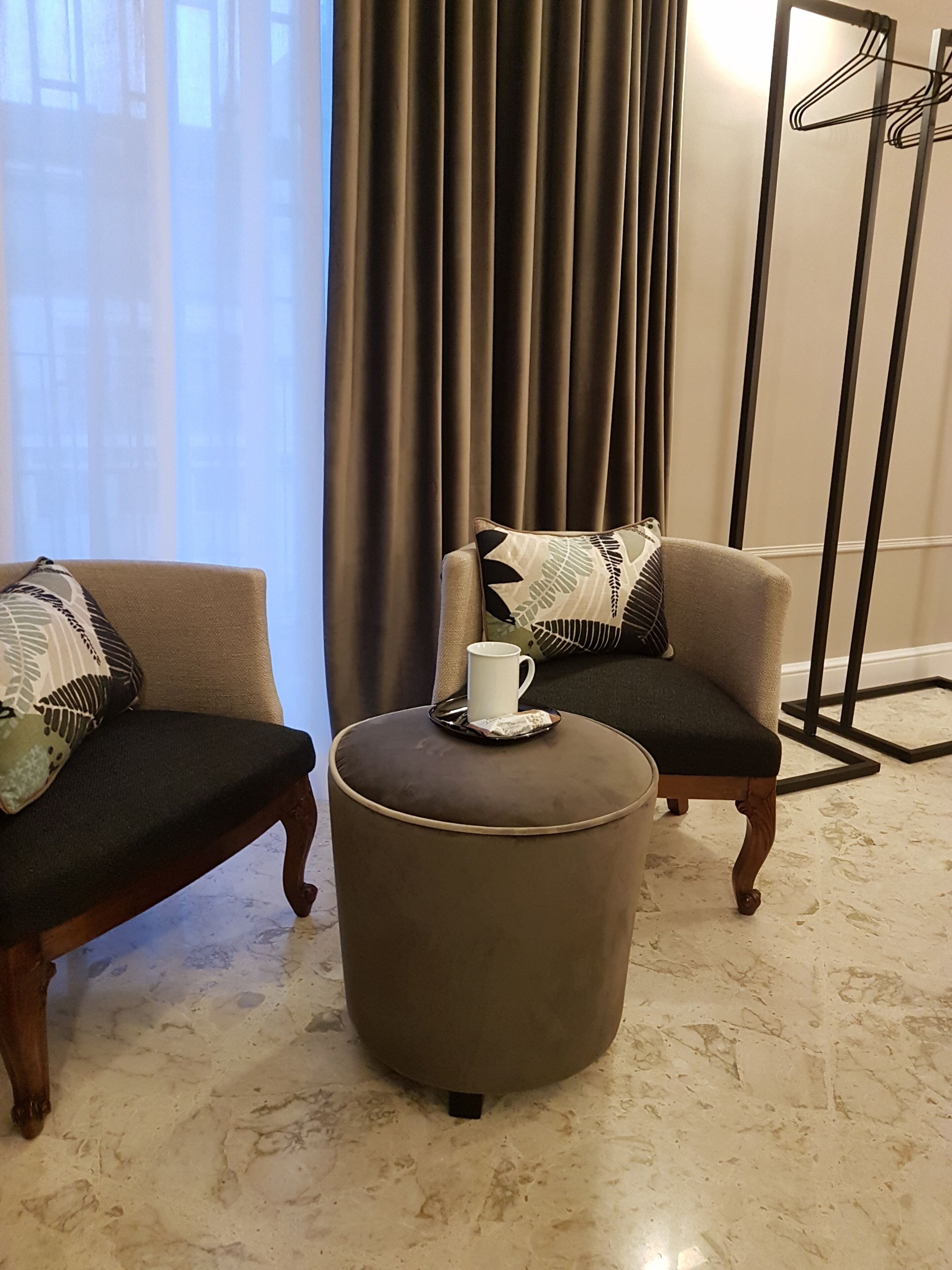 Une pièce comprenant deux fauteuils, un petit pouf et un lampadaire.