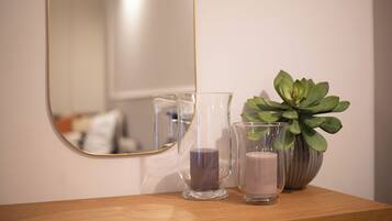 A wooden surface with two clear glass candle holders and a potted plant.