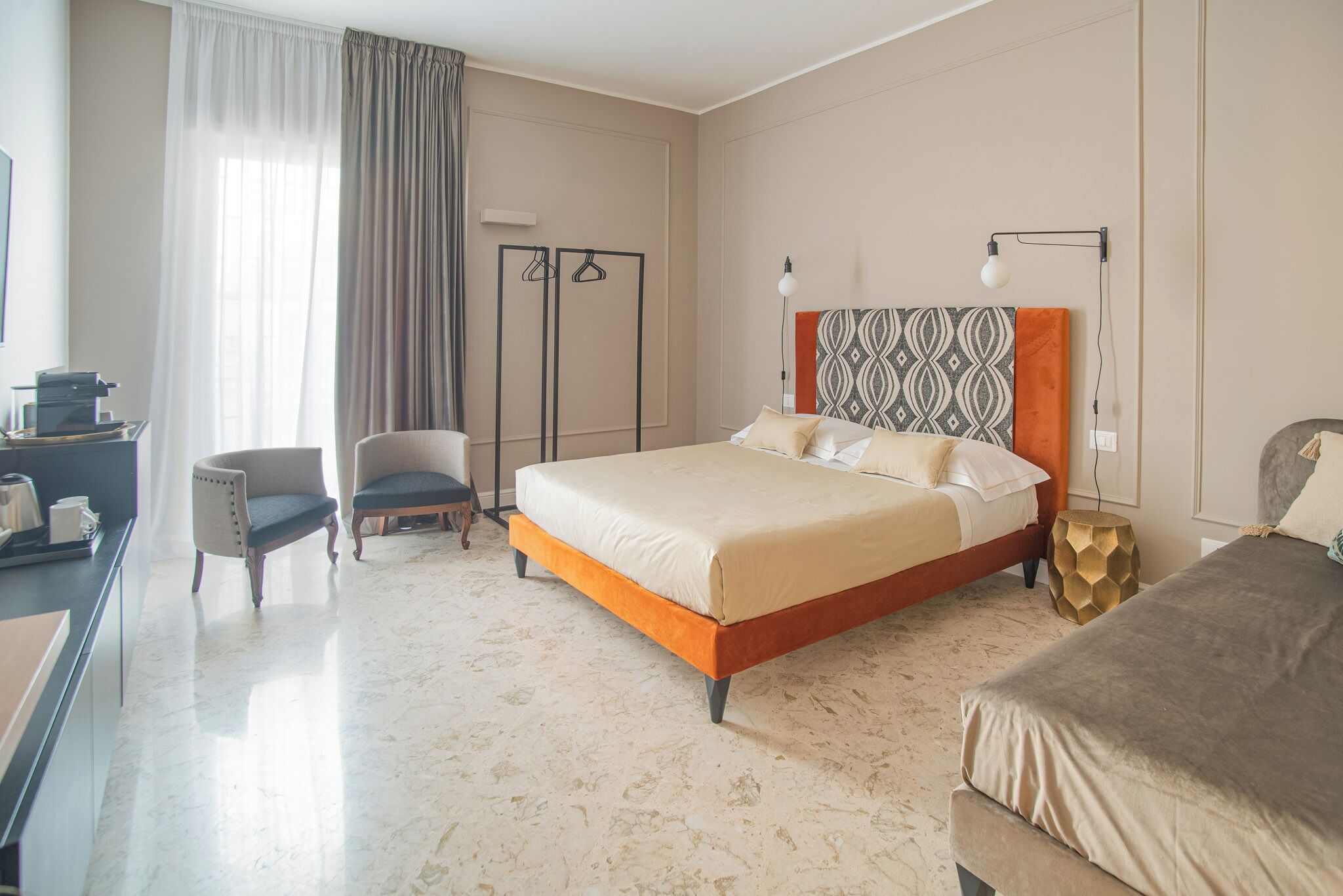 A hotel room with a bed, a chair, a desk, and a wardrobe.