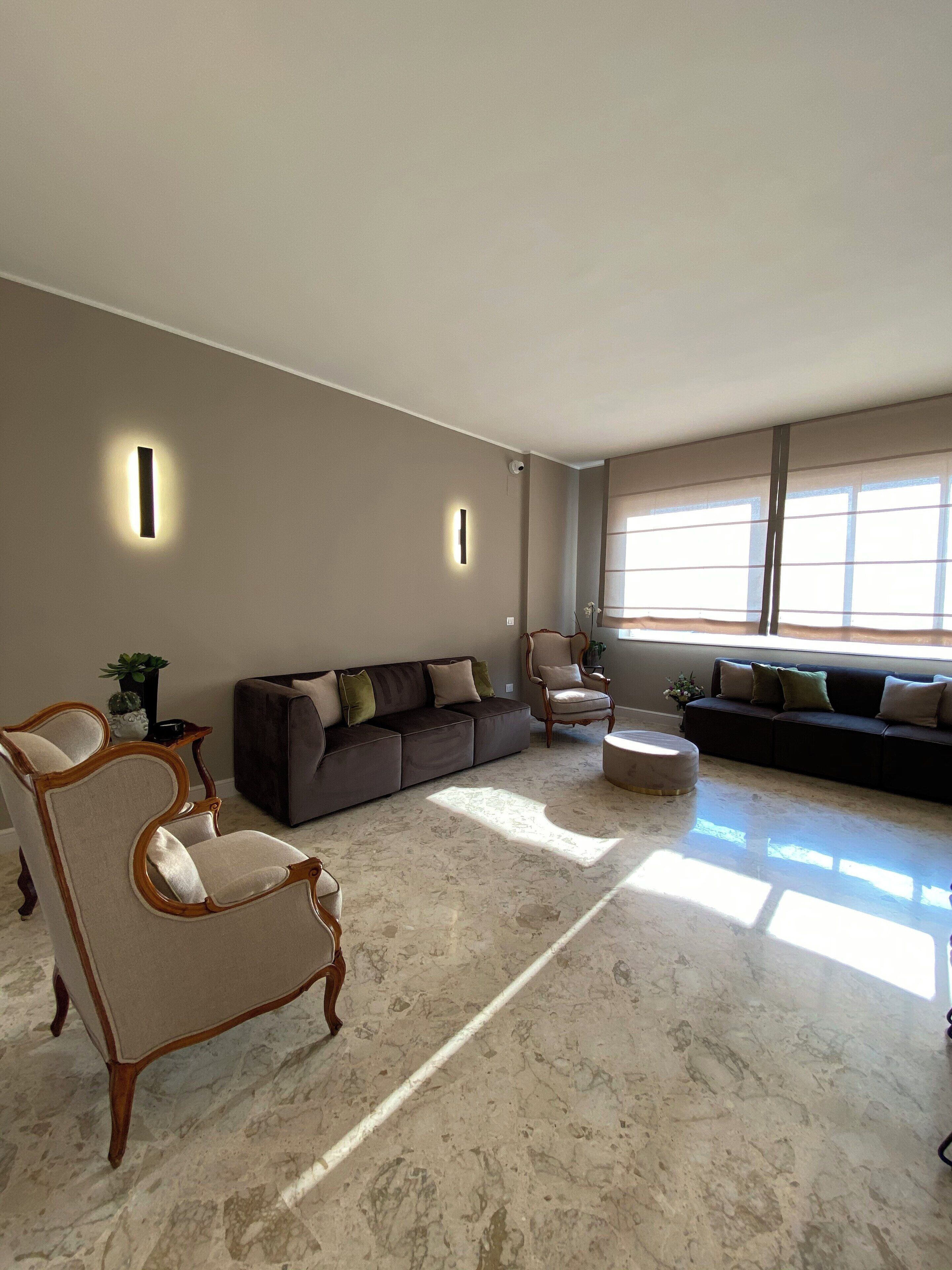 A spacious living room with a large sectional sofa, a wooden armchair, and a round ottoman.
