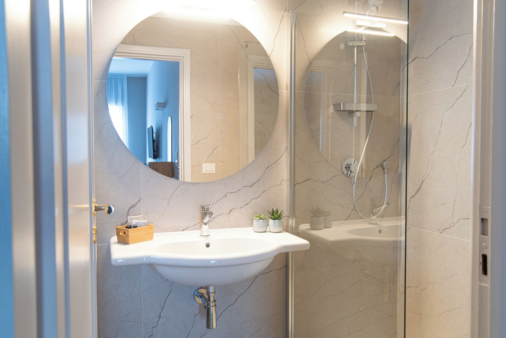 A bathroom with a white sink, a mirror, and a glass-enclosed shower.