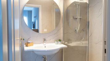 A bathroom with a white sink, a mirror, and a glass-enclosed shower.