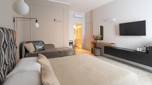 A modern hotel room with a large bed, a sofa, a TV, and a bedside table. - Casa Almika Sparano (Bari)