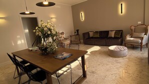 A modern living room with a dining area, featuring a wooden table, black chairs, a sofa, and a round ottoman. - Casa Almika Sparano (Bari)