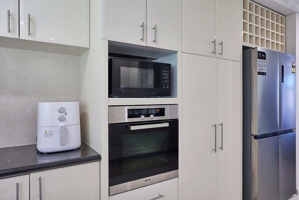 A kitchen with a microwave, oven, and refrigerator.