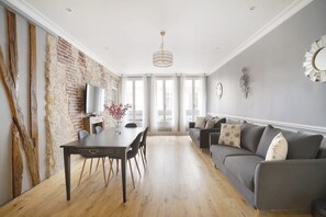 A modern living room with a dining table, sofa, and a chandelier. - Sublim Apartment Center of Paris Opera (Paris)