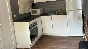 Eine kleine Küche mit weißen Schränken, einer Mikrowelle, einer Kaffeemaschine und einem Kühlschrank.