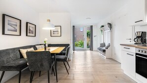 Una cocina moderna con comedor, muebles blancos y vistas al exterior.