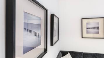 Una habitación con un sofá gris, un cuadro enmarcado en la pared y una pared blanca.