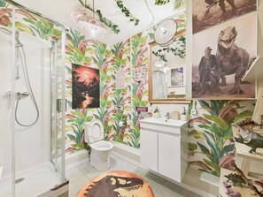 Ein Badezimmer mit Dusche, Toilette, Waschbecken und Dinosaurier-Dekorationen.