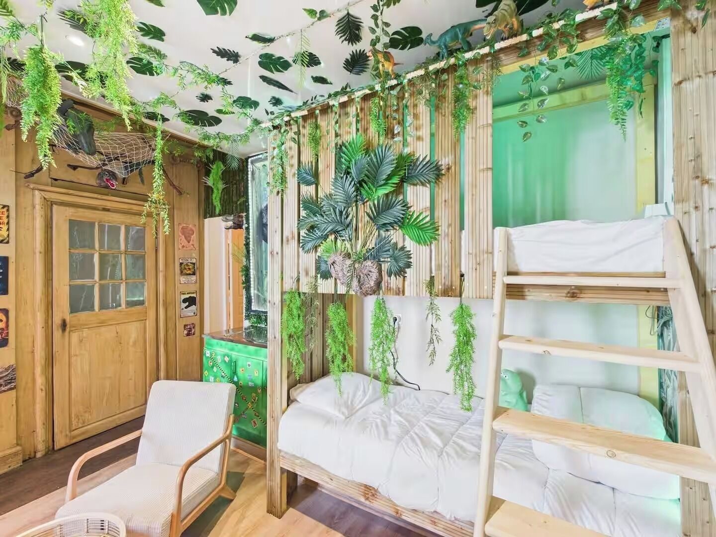 Ein Zimmer mit einem Etagenbett, einem Sessel und einem grünen Schrank.