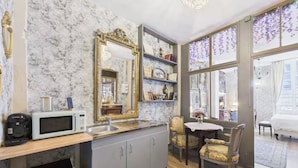 A compact kitchen with a marble backsplash, a large mirror, and a dining area with a view of the city. - Jol Tourisme (Troyes)
