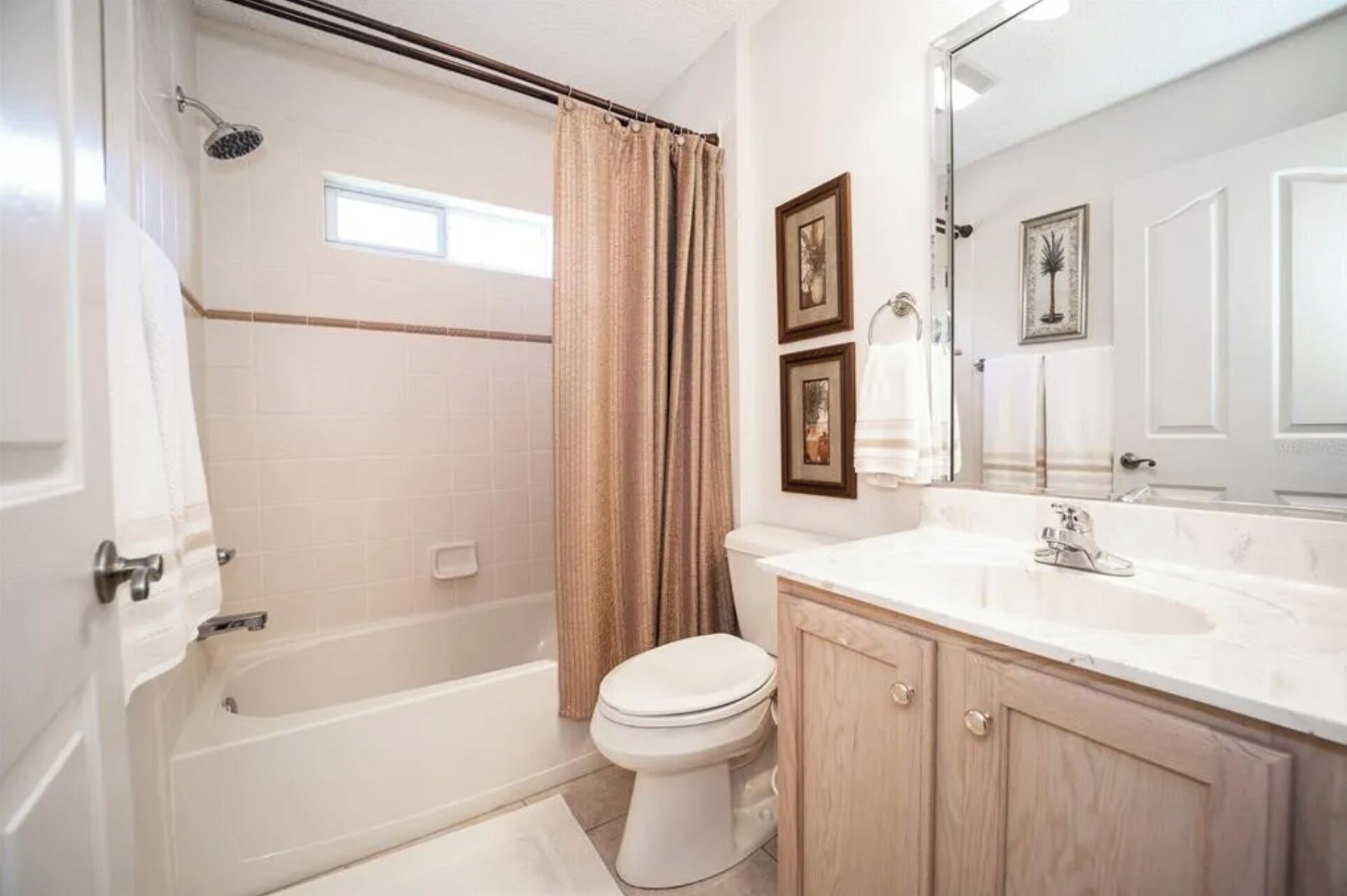 A bathroom with a bathtub, toilet, and vanity with a mirror.