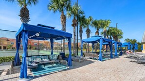 Een zwembadgedeelte met blauwe parasols, ligbedden en een klein zwembad.
