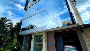 A modern hotel with a glass facade, a car parked in the driveway, and a motorcycle outside. - SONQU TARAPOTO HOTEL  (Tarapoto)