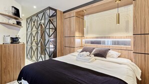 A modern bedroom with a large bed, wooden headboard, and built-in shelves.