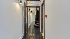 A hallway with a polished black marble floor, a wooden door frame, and a staircase with a wooden railing.