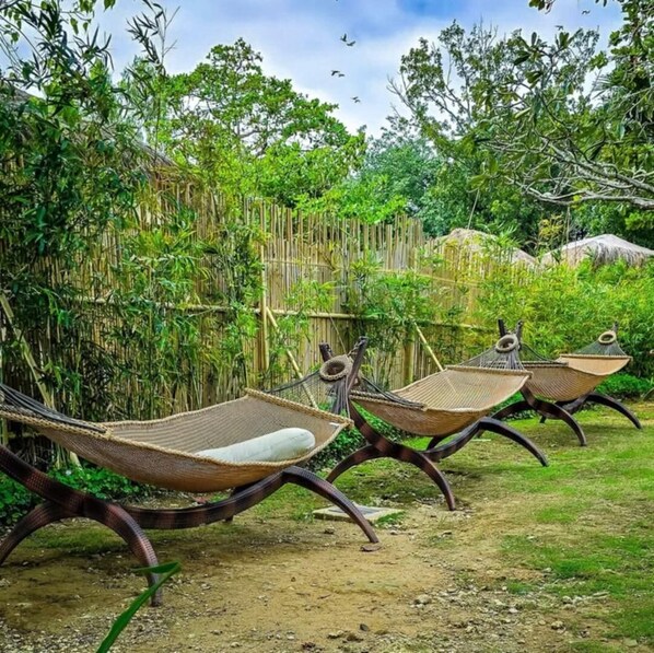A row of outdoor hammocks in a lush garden setting. - 1br condo at mactan near the baech (Lapu-Lapu)