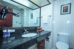Un baño con lavamanos, espejo e inodoro.