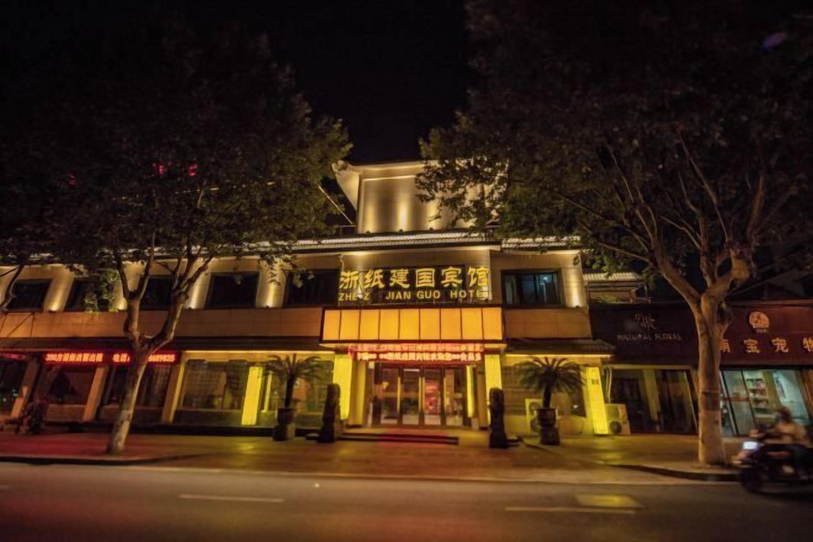 Un hotel con un letrero llamativo en caracteres chinos, fachada moderna y alfombra roja en la entrada.