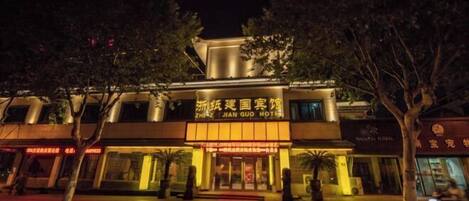 Un hotel con un letrero llamativo en caracteres chinos, fachada moderna y alfombra roja en la entrada.
