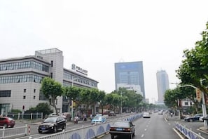 A city street with modern buildings, a clear sky, and cars on the road. - Zhezhi Jianguo Hotel (Lu Xun's hometown) (Shaoxing)