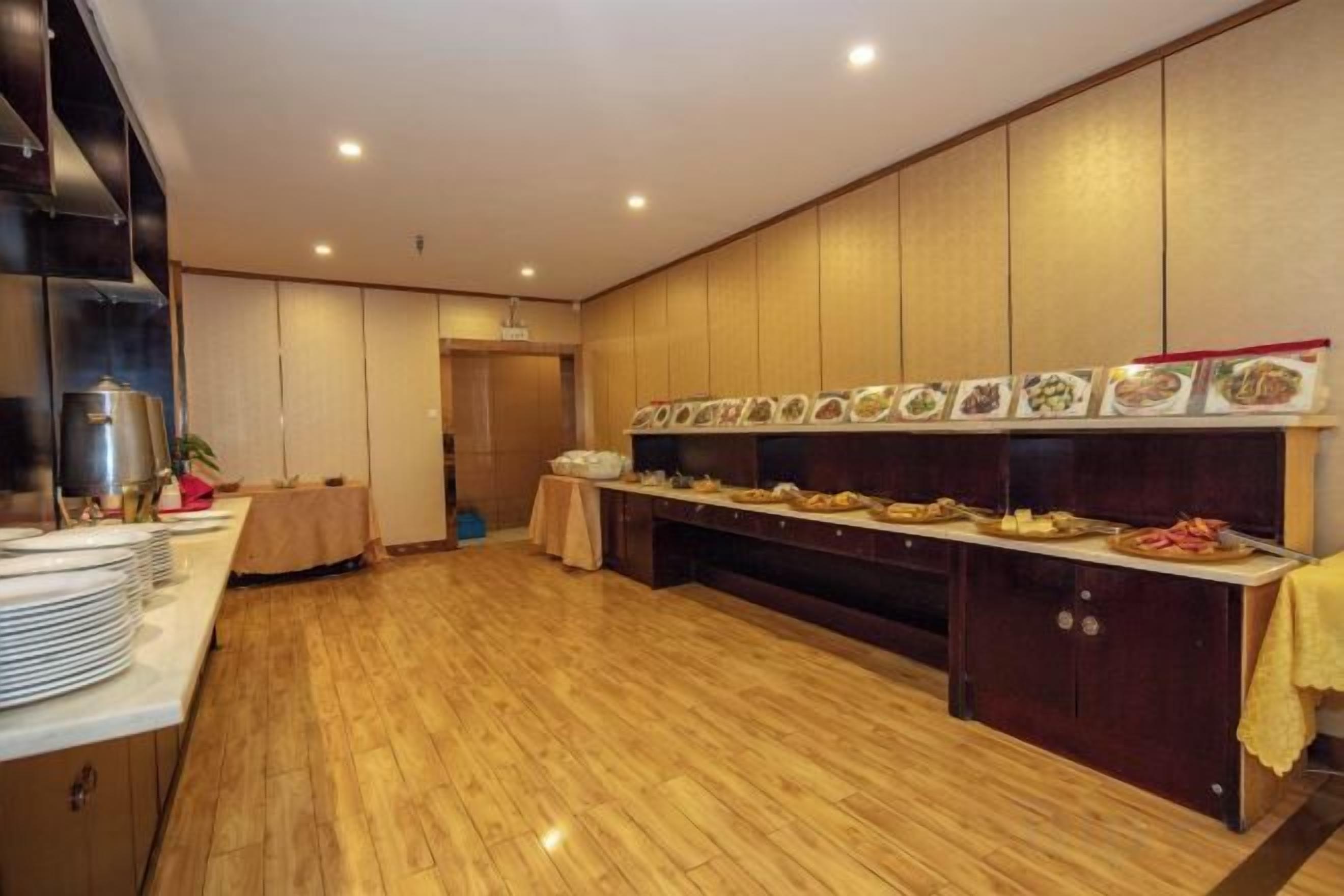 A buffet setup with multiple food stations, a wooden floor, and a kitchen area with cabinets.