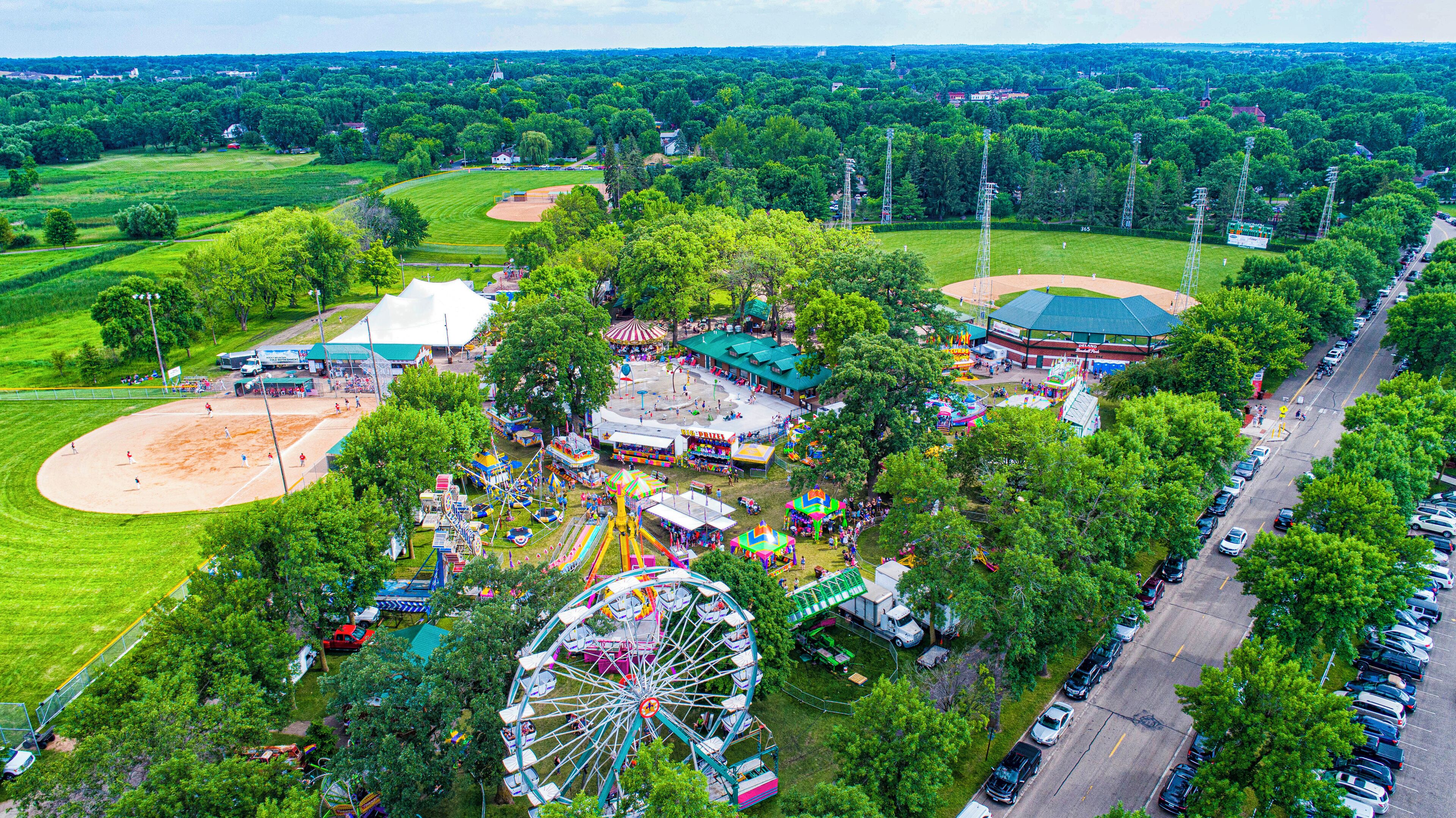 Vista aérea de un parque con un campo de béisbol, una noria y diversas atracciones.