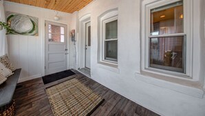 A clean, modern entryway with a wooden ceiling, white walls, and a black doormat. - Charming Downtown Retreat for Weddings, Weekends & Outdoor Fun! (Delano)