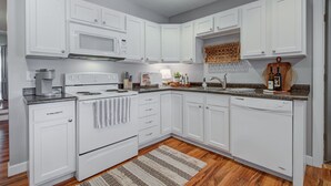 A modern kitchen with white cabinetry, a microwave, stove, and dishwasher. - Charming Downtown Retreat for Weddings, Weekends & Outdoor Fun! (Delano)
