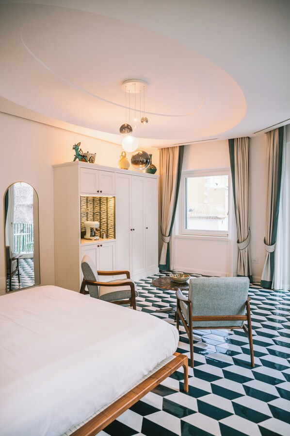 Ein Hotelzimmer mit Bett, Schrank, Stuhl, kleinem Tisch und einem fenster mit Vorhängen.