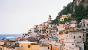 A coastal town with densely packed buildings, some with balconies, and a prominent church tower. - Residenza Dea Amalfi (Amalfi)