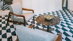 A room with a checkered floor, a white wardrobe, a round table with a bowl, and a chair. - Residenza Dea Amalfi (Amalfi)