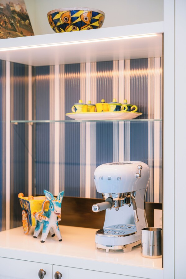 Une cuisine équipée d’une machine à café, ornée d’une statuette d’âne décorative et d’une théière jaune posée sur une étagère.