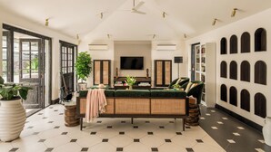 A spacious living room with a large sofa, a flat-screen TV, and a bookshelf. - Viraam Estate by RÊVE/Infinity heated pool with caretaker/Chef (Assagao)