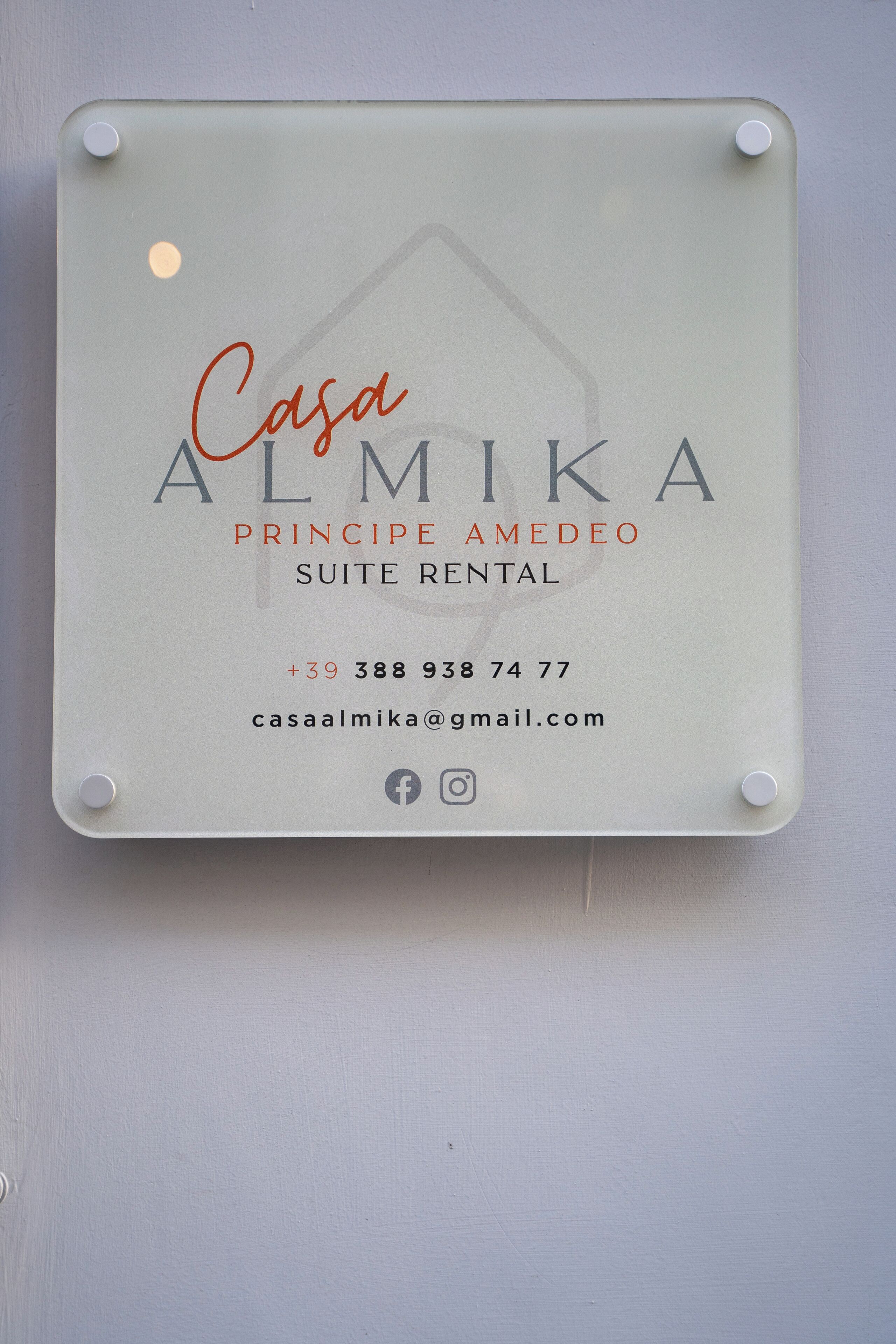 Visitenkarte von Casa Almika, einer Marke von Amedeo, mit Kontaktinformationen und Social-Media-Symbolen.