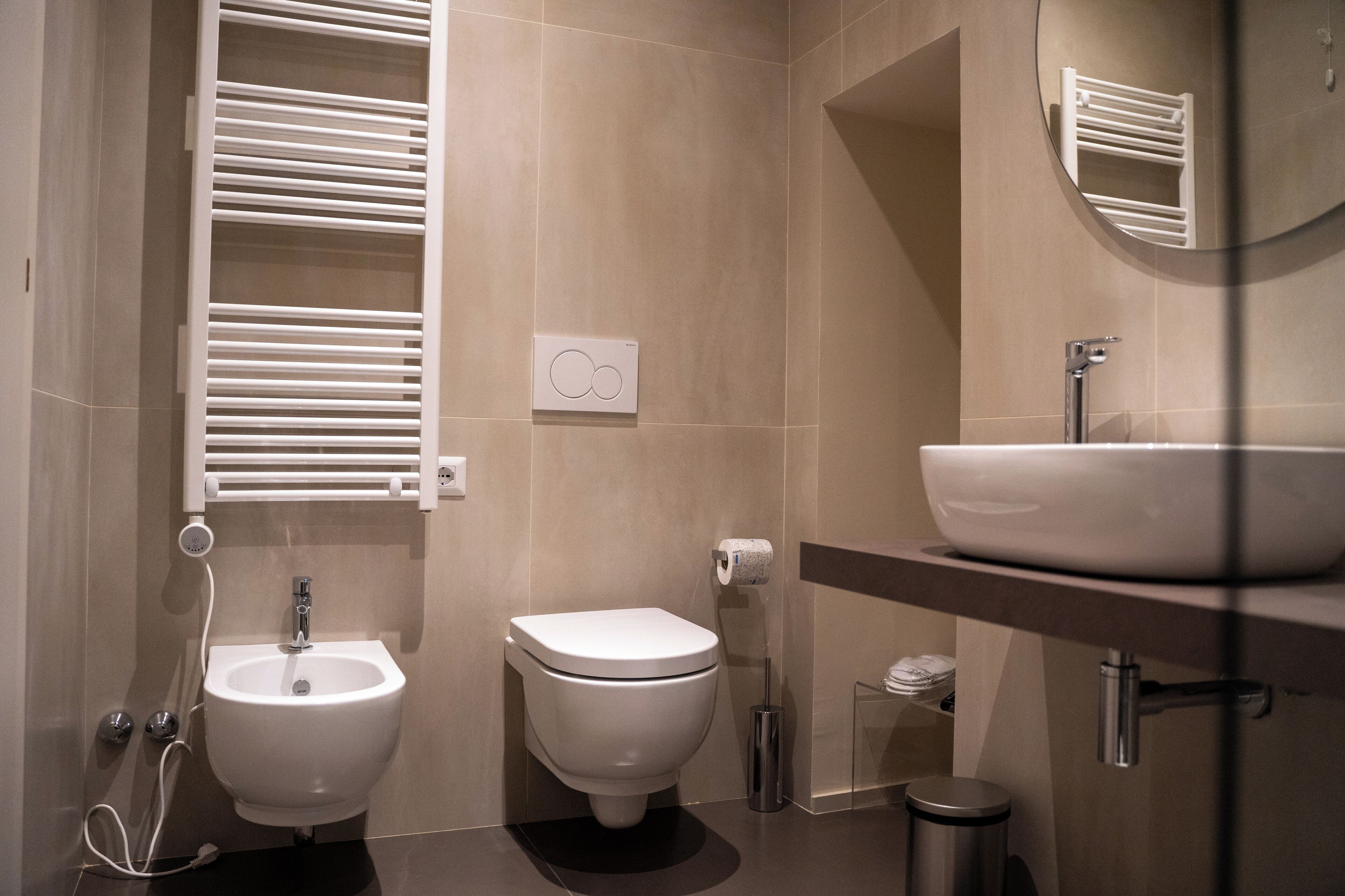 A modern bathroom with a bidet, a sink, and a mirror.